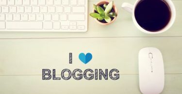 I Love Blogging concept with workstation on a light green wooden desk